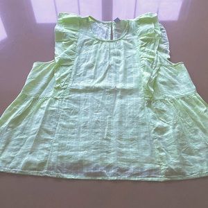 Sleeveless pastel green blouse with frills and a button detail at the back.